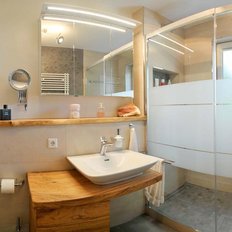 Das Badezimmer zeigt eine stilvolle Dusche mit Glaswänden und eine dekorative Orchidee auf dem Holzregal.