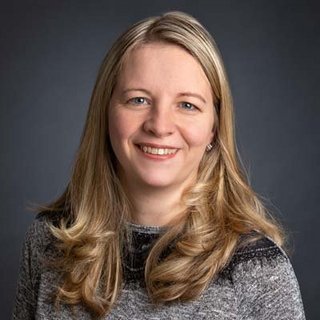 Porträt einer freundlichen Frau in grauem Pullover Die Frau hat eine freundliche Ausstrahlung, mit blonden Locken und einem grauen Pullover, der gut zu ihrem Teint passt.