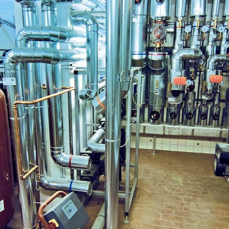 Komplexe Rohrleitungen und Ventile in einem technischen Raum, der für die Heizungs- und Wasserversorgung konzipiert ist.