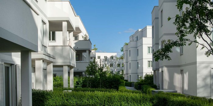 Architektonisch ansprechende Wohnhäuser, die in einer ruhigen Umgebung mit gepflegten Hecken und Bäumen stehen.