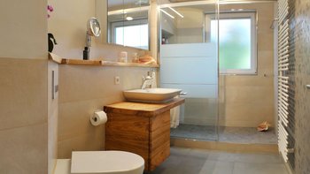 Das Badezimmer zeigt eine Dusche mit Glasabtrennung und eine stilvolle Holzkommode, die für Stauraum sorgt.