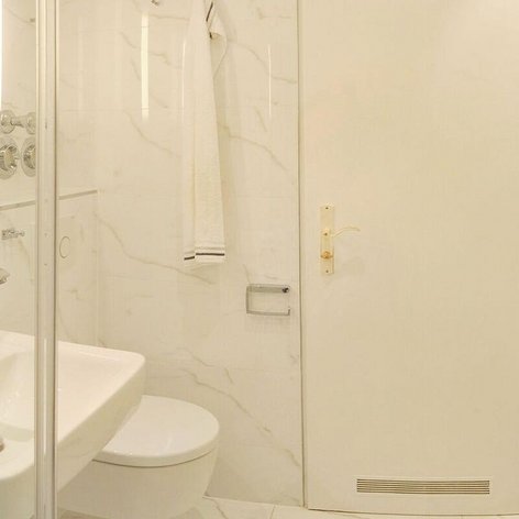Das Badezimmer zeigt eine helle, minimalistische Gestaltung mit einem großen Spiegel und einem Handtuch, das an der Wand hängt.
