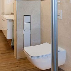 Das Badezimmer zeigt eine stilvolle Kombination aus Fliesen und Holz, mit einem schlichten WC und einer Glasdusche.