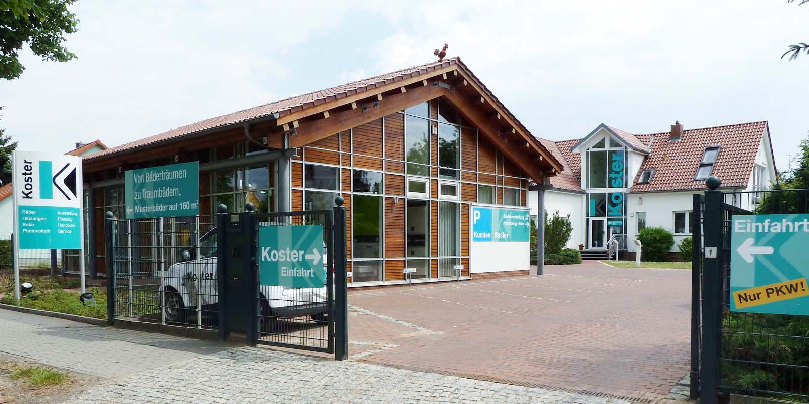 Die Fassade des Koster-Geschäfts zeigt große Fenster und ein einladendes Eingangsschild, das Kunden zu Traum-Bädern einlädt.