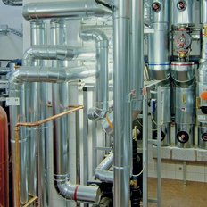 Komplexe Anordnung von Metallrohren und Ventilen in einem technischen Raum, der für industrielle Anwendungen konzipiert ist.