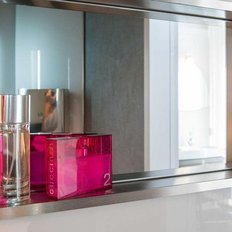 Ein eleganter Spiegel reflektiert zwei Parfümflaschen, eine in klarem Glas und die andere in leuchtendem Pink.