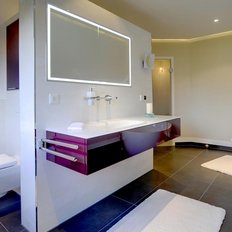 Das stilvolle Badezimmer zeigt eine minimalistische Einrichtung mit dunklen Fliesen und einem großen, runden Badewanne.