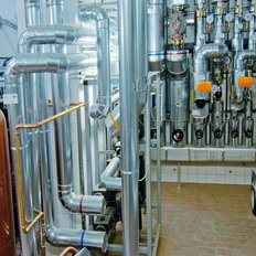 Die industrielle Umgebung zeigt eine komplexe Anordnung von Rohren und Ventilen, die für Heizungs- oder Kühlungssysteme genutzt werden.