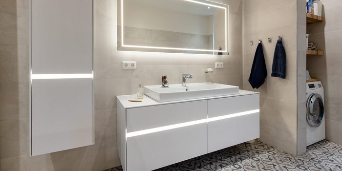 Ein modernes Badezimmer mit einem eleganten Waschbecken und einem beleuchteten Spiegel, der eine stilvolle Atmosphäre schafft.