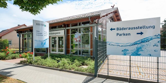 Die Fassade eines Geschäftshauses mit einem einladenden Eingangsbereich und blühenden Rosen im Vordergrund.