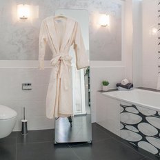 Ein elegantes Badezimmer mit einem weißen Bademantel, der an einem Spiegel hängt, und modernen Armaturen in sanften Farben.