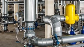 Moderne Rohrleitungen und Ventile in einer Fabrikhalle In einer Fabrikhalle verlaufen zahlreiche Metallrohre, die miteinander verbunden sind, während ein gelbes Ventil hervorsticht.
