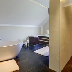 Das Badezimmer bietet eine harmonische Kombination aus einer weißen Badewanne und einer dunklen Duschwand, die Ruhe ausstrahlt.